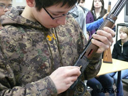 A students handles a cutaway gun that is nonfunctioning and allows a view inside the action