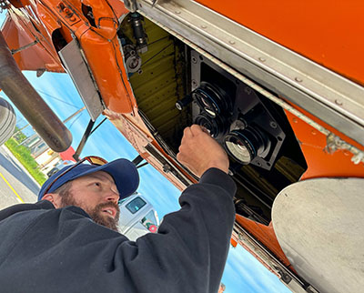 Wildlife biologist Nate Pamperin under the plane cleaning the camera lens before the flight