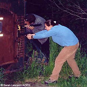 Rick Sinnott directs a light as biologist Jessy Coltrane aims a dart pistol