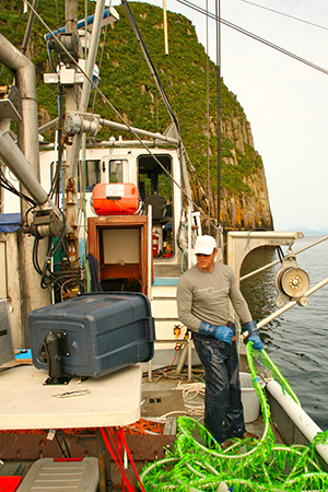 Biologist Philip Tschersich holds the cable attached to the  video camera under the KHiC The green fairing on the cable streamlines water flow around the cable reducing drag and cable vibration He39s checking a monitor protected by the plastic actionpacker box Photo by Carrie Worton